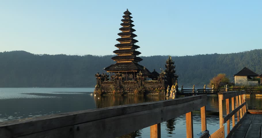 Ascending slow motion shot of a historic hindu temple on bali at volcano lake batur overlooking the calm sea and beautiful landscape in indonesia Royalty-Free Stock Footage #1105460689