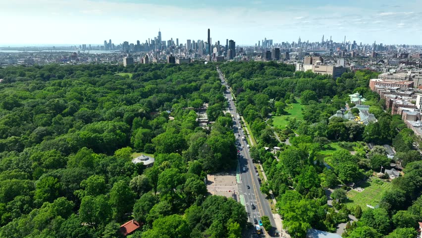 Wide panoramic shot of Prospect Park in Brooklyn, New York. Brooklyn and Manhattan skylines in distance. Aerial establishing shot in summer. Royalty-Free Stock Footage #1105464147