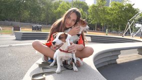 Two dogs and long haired teenager girl sitting in the park happy smiling. hugging cuddling, petting two pets small white Jack Russell terriers friends, Summer in big city. Pets love and trust video
