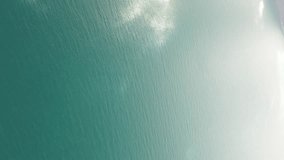 Abstract aerial sea summer ocean sunset nature background. Small waves on water surface in motion blur with golden bokeh lights from sun. Holiday, vacation and recreational concept. Vertical video