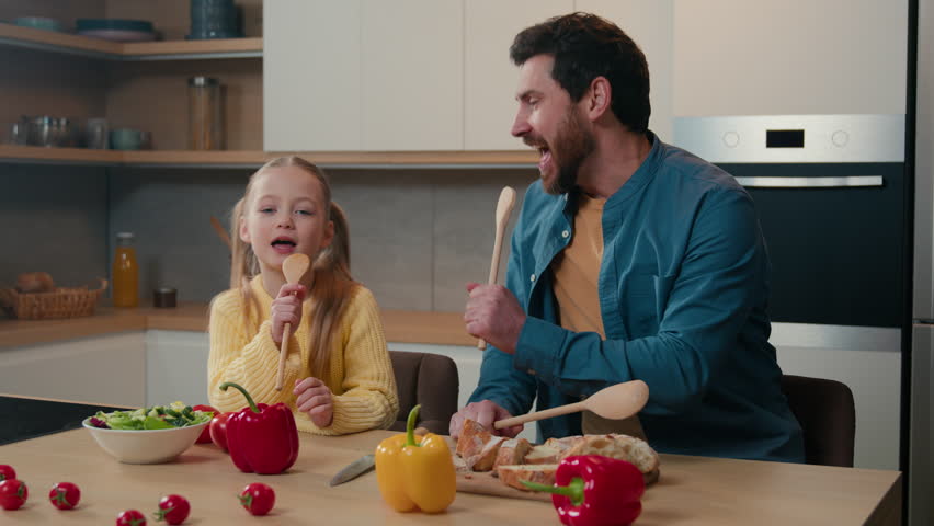 Caucasian father dad little child girl cute kid daughter happy family at home domestic kitchen singing in wooden spoons together sing song having fun fooling around playing party breakfast cooking Royalty-Free Stock Footage #1105471547