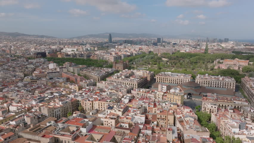 Forwards fly above urban borough in metropolis. Aerial panoramic view of buildings and Ciutadella Park. Barcelona, Spain