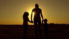 Silhouettes at sunset. Mother daughter and son are on the field . The concept is a happy family. 4k video.