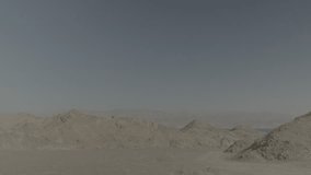Desert mountains surrounding the red sea at midday. a very little portion of the sea is visible at the lower right corner, while big portion goes for the empty skies. a 4K. F-log clip.