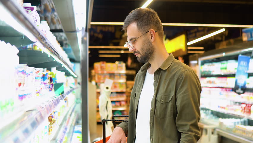 A man shopping dairy product in grocery store. Side view of handsome man buying milk Royalty-Free Stock Footage #1105489931
