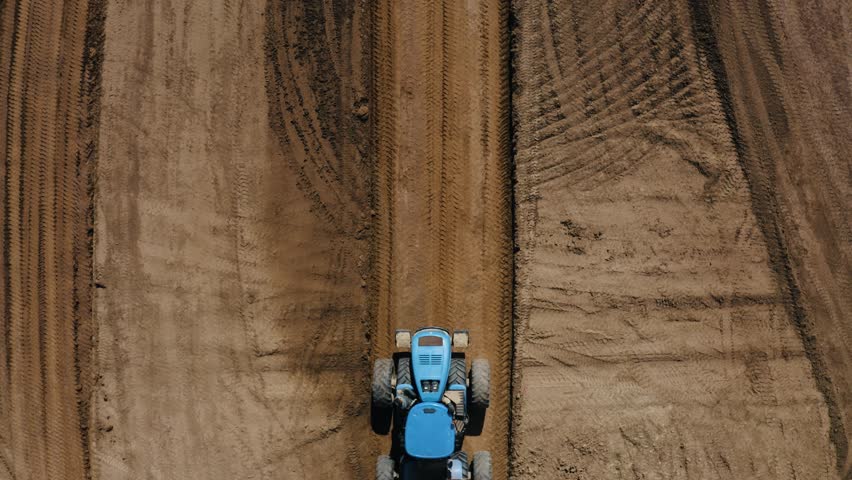 Overhead drone shot of a tractor towing loads of dirt. Royalty-Free Stock Footage #1105492567