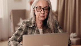Close up portrait of senior woman with glasses relaxing at home or working online browsing products in internet store reading news checking email or social media profile on laptop computer indoors - Powered by Shutterstock - Get 15% off with code: PIKWIZARD15