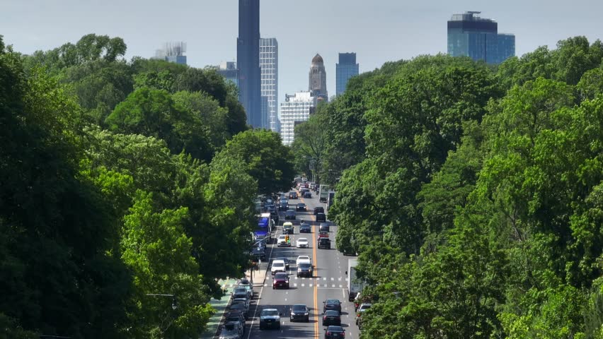Long aerial zoom shot between thick foliage of trees in Prospect Park. Drone tilt up reveals The Brooklyn Tower in New York. Royalty-Free Stock Footage #1105496457