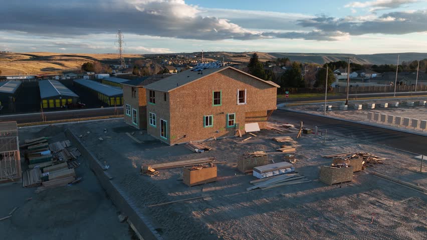 Orbiting aerial view of the first houses in a neighborhood being built at sunset.