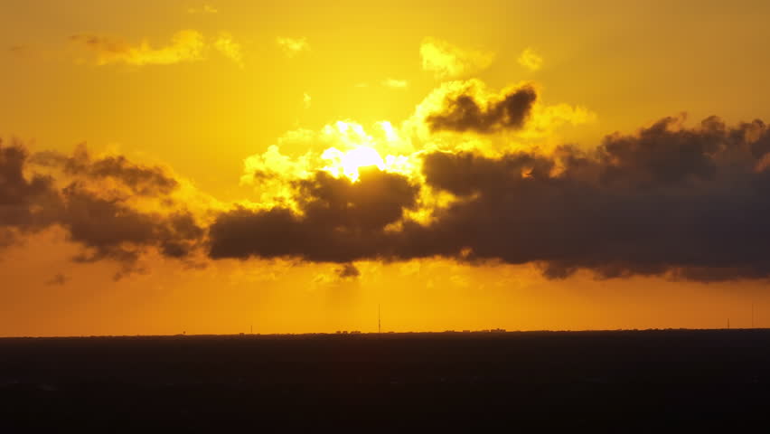 Sunset with bright setting sun behind colorful orange and yellow clouds. Panoramic skyscape