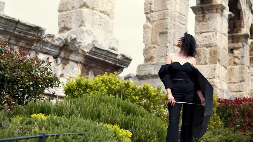 Delighted young executive woman in black enyoing with great view of Colosseum in Pula. 