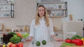Young woman food blogger cooking salad in front of smartphone camera while recording vlog video and live streaming at home in kitchen.