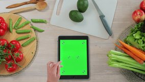 Young woman scrolls through recipes on her tablet in the kitchen. Application for cooking. Healthy food concept. - Powered by Shutterstock - Get 15% off with code: PIKWIZARD15