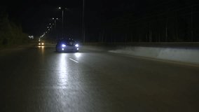 A dark road in the night. Clip. A small slow-moving car that moves slowly in the night around the lights