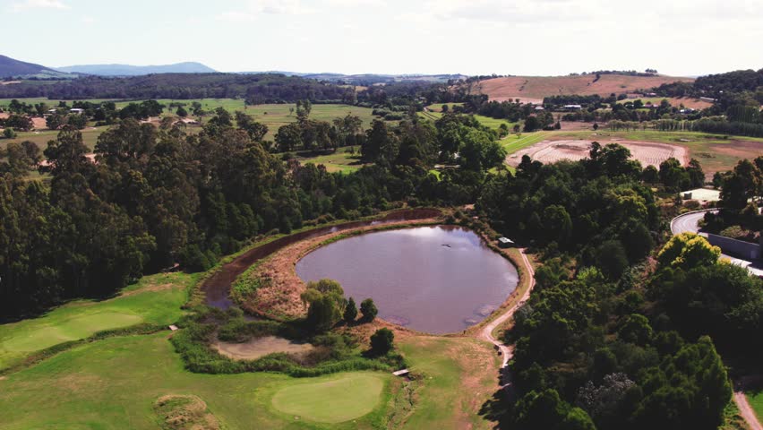 Aerial drone forward moving shot over wooden houses beside small lakes surrounded by lush green vegetation at daytime.