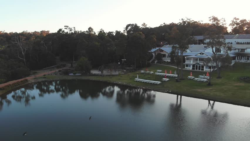 Aerial, luxurious lakeside house in forest with private dock in the evening