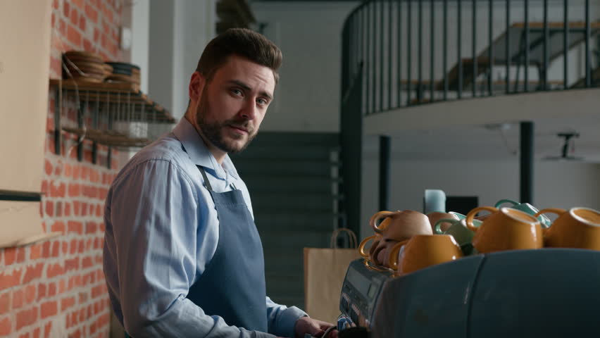 Smiling caucasian man waiter professional barista bartender make coffee behind counter in cafeteria serve customer in restaurant happy male cafe employee staff small business owner looking at camera