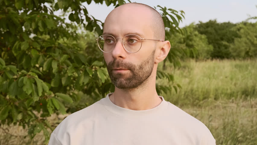closeup young charismatic man wipes gold-rimmed glasses with napkin, checks cleanliness and transparency of lenses, concept cleaning routine, lens protection, lens care essentials, eyewear cleanliness