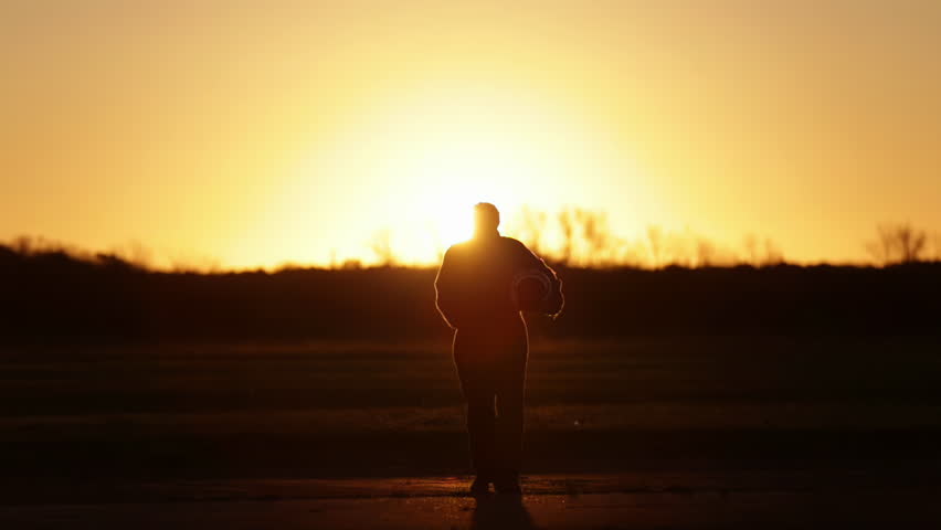 Silhouette of an Air Force Pilot Walking With His Flying Helmet During Sunset at Air Base. 4K Resolution. Royalty-Free Stock Footage #1105517399