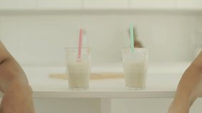 Two protein shake glasses with straws are on the kitchen counter. A couple has just worked out and takes them while resting. - Powered by Shutterstock - Get 15% off with code: PIKWIZARD15
