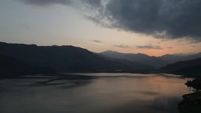 Cinematic drone flight through the Nepal Valley in Pokhara overlooking the sunset sky with birds. 4k footage