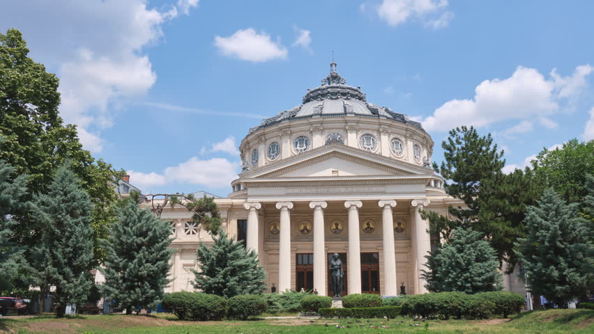Romanian Athenaeum (Ateneul Roman), a landmark in Bucharest, Romania. Timelapse of white Summer clouds above this domed, circular concert hall building, opened in 1888. Royalty-Free Stock Footage #1105529281