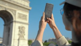Young blogger taking a photo on the phone of the Arc de Triomphe