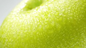 Capturing the individual droplets in exquisite detail. The smooth curves of the apple's skin are magnified, revealing tiny imperfections that only enhance its organic charm. Green apple background. 4K - Powered by Shutterstock - Get 15% off with code: PIKWIZARD15