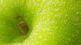 The vibrant and refreshing beauty of a green apple takes center stage. perfectly shaped green apple. Its smooth skin glistens under the soft, diffused lighting. Macro video. Green apple background
