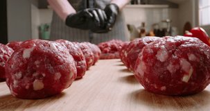 Chef prepares blanks for meatballs from fresh minced meat in a kitchen with subdued lighting, Professional promotional video Advertising. Artistic video with hamburger patties vegetables and spices