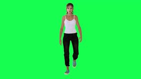 Slim girl in white dress black pants and blue shoes walking from front angle on green screen