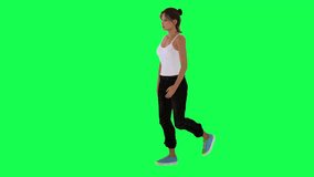 Slim girl in white dress black pants and blue shoes walking from right angle on green screen