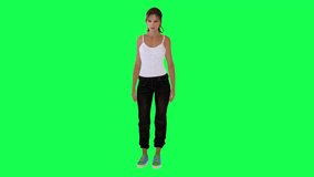 Respectable young lady in white dress black pants and blue shoes waiting from opposite angle on green screen