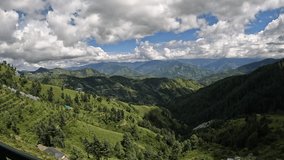 Timelapse of clouds and sky in the mountains. High quality 4k video of clouds moving over a green mountain forest with clear blue sky.