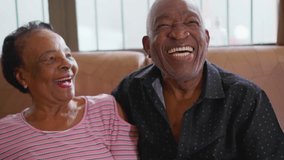 Senior couple laughing and smiling sitting on couch. A black Brazilian older husband and wife authentic real life laugh and smile, happy relationship in old age retirement - Powered by Shutterstock - Get 15% off with code: PIKWIZARD15