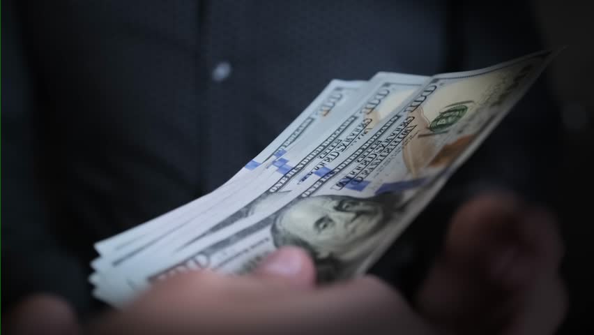 On dark background, man in classic black clothes takes money and counts dollar bills close up. Financial business concept. Royalty-Free Stock Footage #1105548057