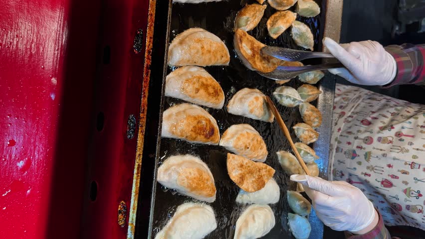 Mandu (Korean Dumplings) at a Korean street food market. Myeongdong night market in Seoul, South Korea. Vertical video.