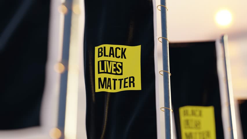 A loop of a vertical flag bearing the text Black Lives Matter gently swayed in the evening breeze.
