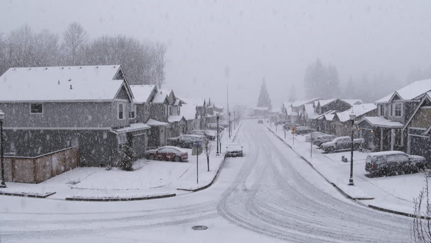 Camera panning shot as snow falls on residential neighborhood and empty streets. Royalty-Free Stock Footage #1105556011
