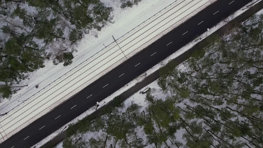 Rotating Aerial view on road in winter time, road surrounded with forest trees. Rural winter area. Top view landscape. shooting from drone. Snow covered road in winter forest