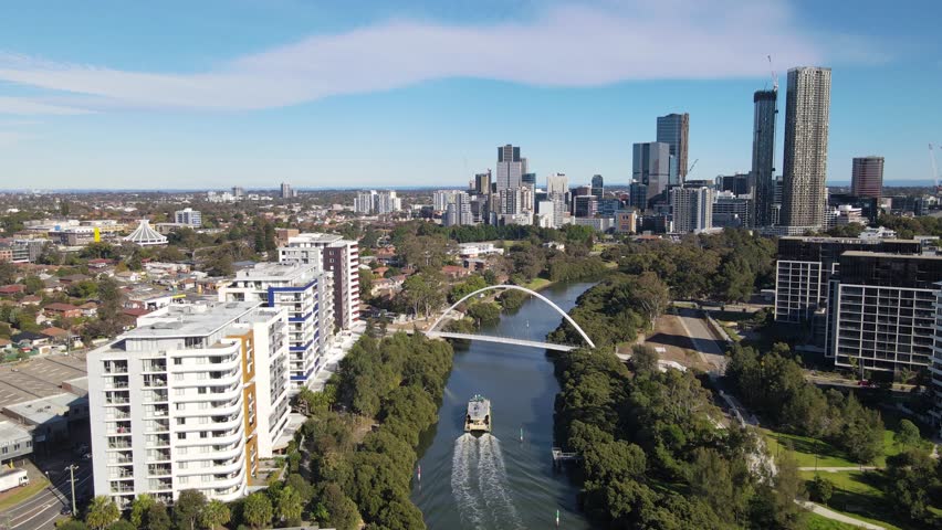 Aerial drone view above Parramatta River in Greater Western Sydney, NSW, Australia with Parramatta CBD in the background as a ferry travels to Parramatta Wharf   Royalty-Free Stock Footage #1105559743