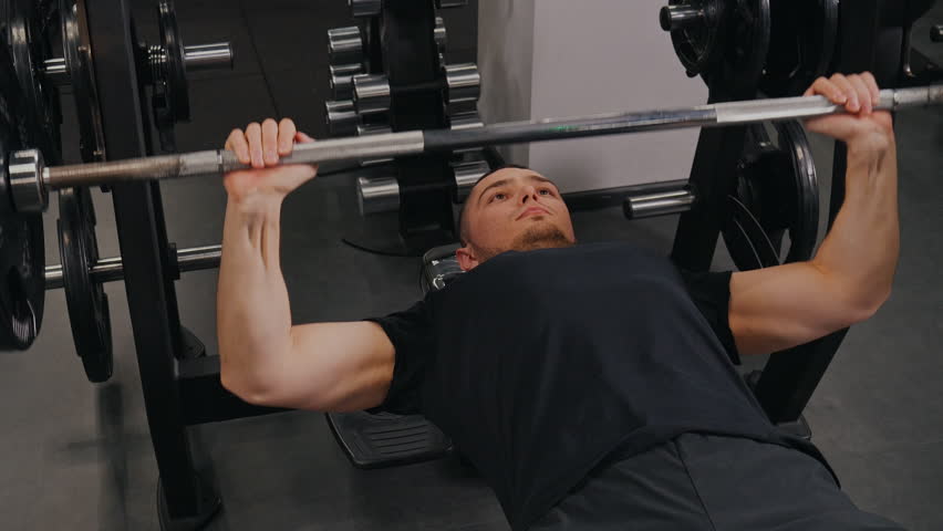 Arms Concentrates, Presses Bodybuilder, Machines Bench. Bodybuilder engages in arm exercises on weight machines and also prioritizes barbell bench presses. Royalty-Free Stock Footage #1105561663