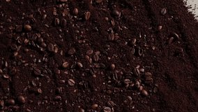 Slow-motion close-up of broken coffee beans and coffee powder splashing on dark background. High quality creative footage for promotional video editing
