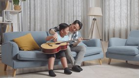 Full Body Of Asian Father Teaching His Son Singing And Playing The Guitar On Sofa At Home
 - Powered by Shutterstock - Get 15% off with code: PIKWIZARD15