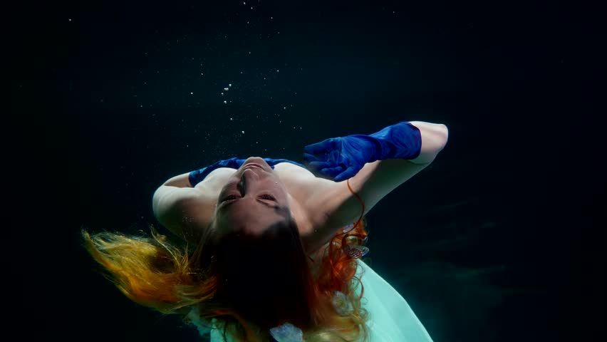 fabulous mermaid diving in mysterious depth, beautiful redhead woman floating alone in dark water
