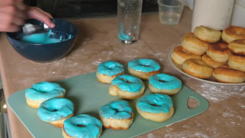 Frying process homemade and delicious donuts on fresh oil in a pan. Blue sugar topping on donuts in a home candy workshop. Pastry, sweet. Making dessert being deep fried. Preparation of donuts