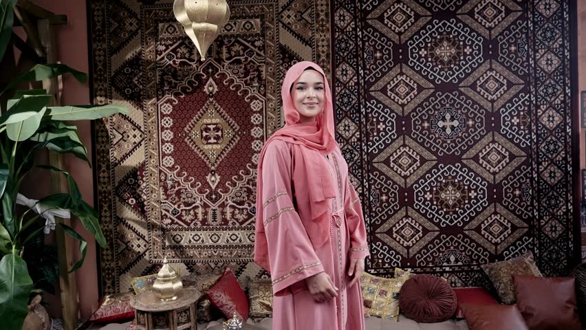 Beautiful young woman with pink colored abaya smiling at camera inside a traditional arab house. Concept about middle eastern cultures and lifestyles  Royalty-Free Stock Footage #1105570609