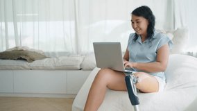 Happy asian woman in prosthetic leg using laptop notebook typing message, chatting on browsing surfing internet social media or working online at home. Leg prosthetic equipment, Amputee concept - Powered by Shutterstock - Get 15% off with code: PIKWIZARD15
