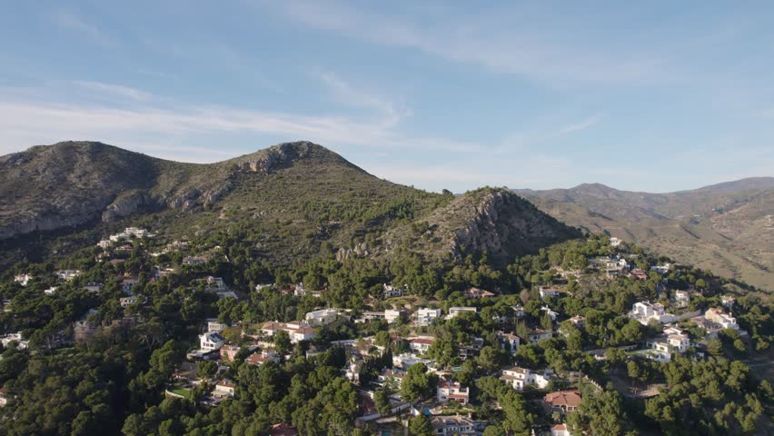 Nestled amidst mountains and valleys. Picturesque houses are scattered amidst the lush greenery of towering trees, creating a harmonious blend of nature and architecture. 