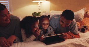 Funny, tablet and family in bedroom at night, bonding and streaming movie, video and relax. Technology, children and parents on bed, laughing or social media for gaming, app or happy together in home